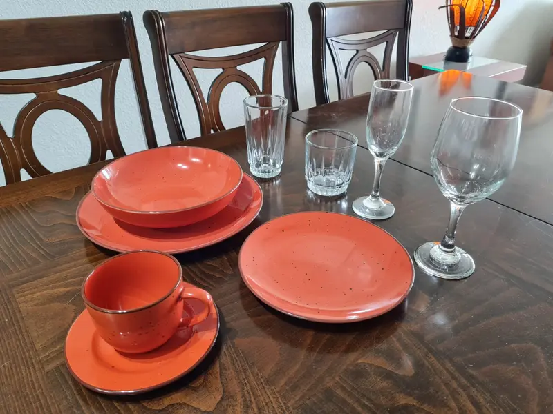 Mesa de comedor dispuesta con vajilla completa y copas